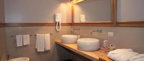 A bathroom with two sinks, a toilet, and a mirror.