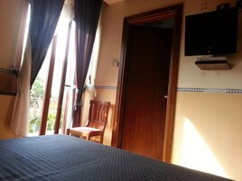 Een slaapkamer met een bed, een stoel, een televisie en een deur.