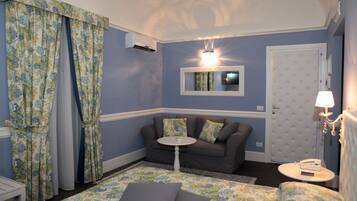 A room with a bed, a sofa, a small table, a lamp, and a door with a mirror above it.