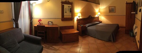Una habitación de hotel con cama, escritorio, silla, cómoda y espejo.