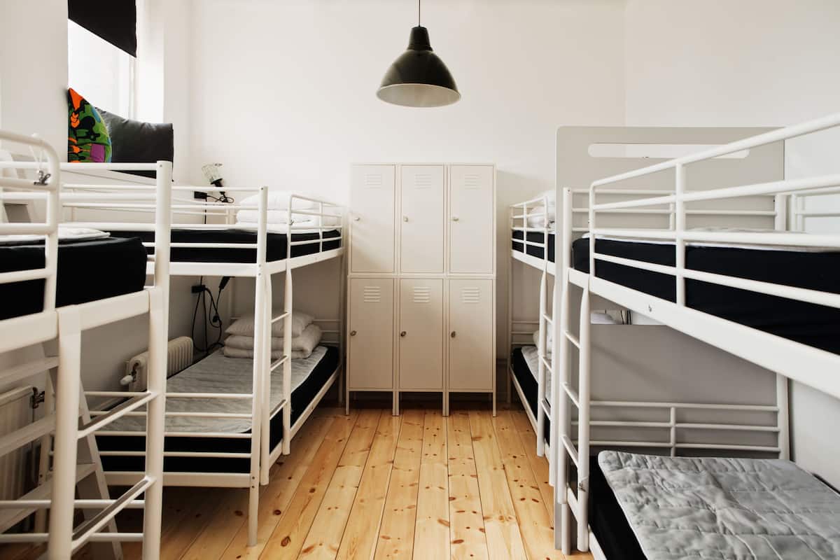 A dormitory room with bunk beds, a wardrobe, and a hanging light fixture.