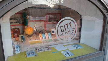 A window display with various travel-related items, including a globe, postcards, and a sign reading "CITY 1994 BACKPACKERS".