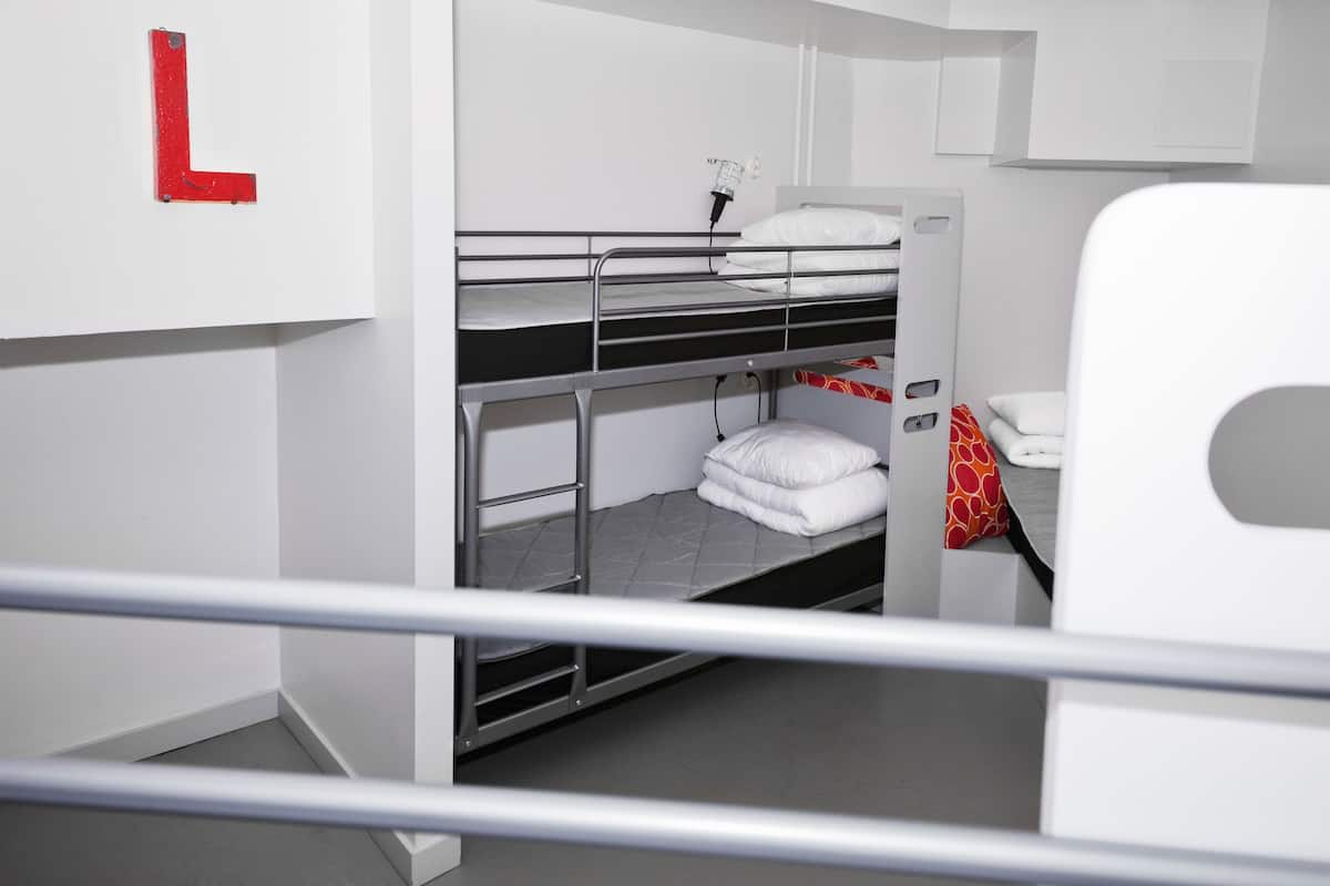A bunk bed room with a white wall and a red 'L' sign.