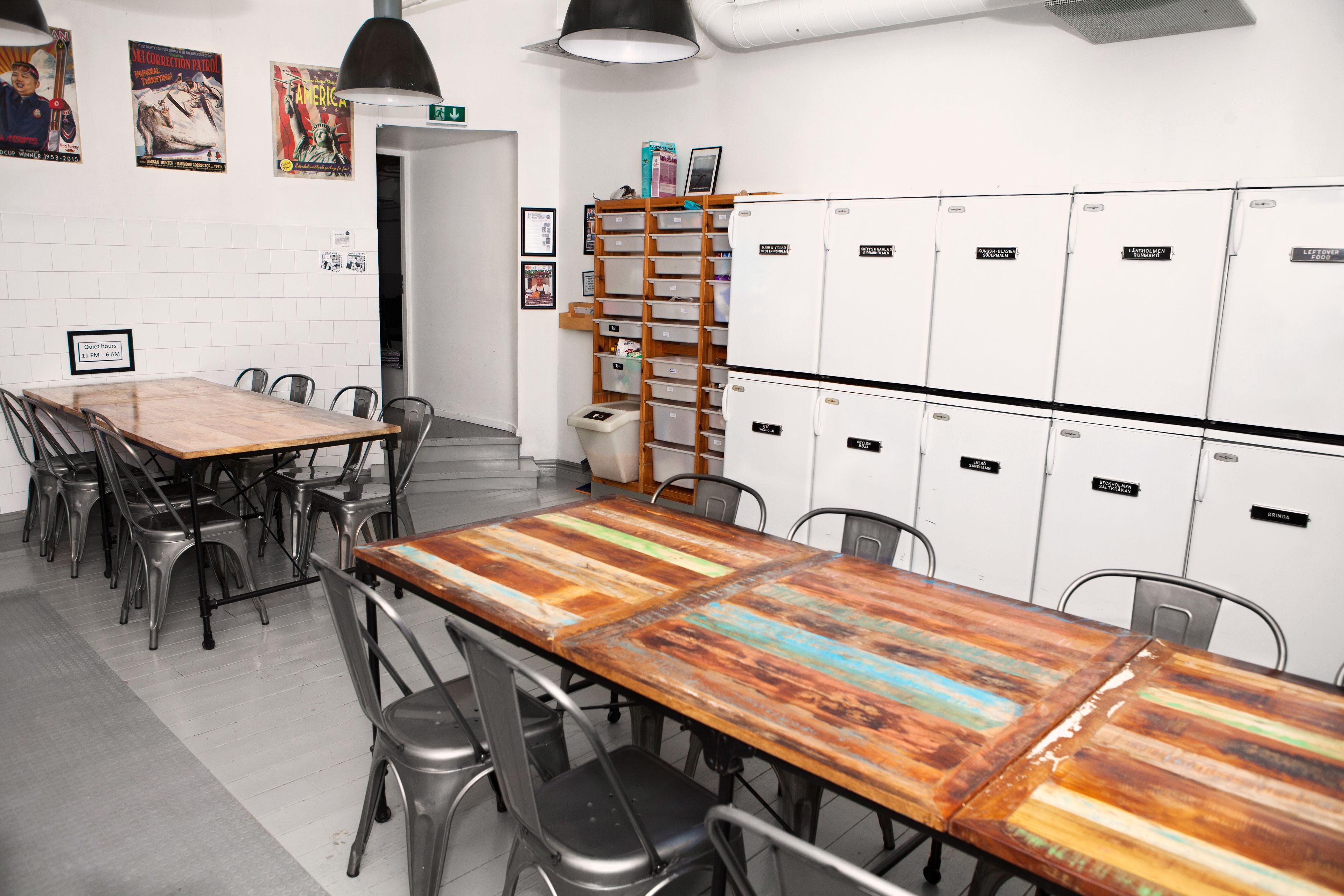 Une salle de conférence avec une longue table en bois, des chaises en métal, des casiers blancs et une petite poubelle.