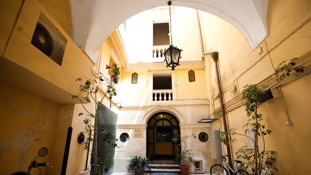 An arched entrance to a building with potted plants and a bicycle. - Azzurretta (Lecce)