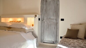 A bedroom with a large bed, a smaller bed, and a wooden door. - Azzurretta (Lecce)