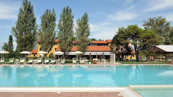 Una piscina al aire libre, sombrillas, sillones reclinables de piscina