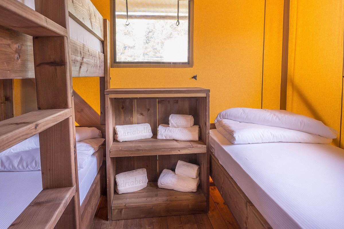 A room with bunk beds, a window, and wooden shelves with towels.