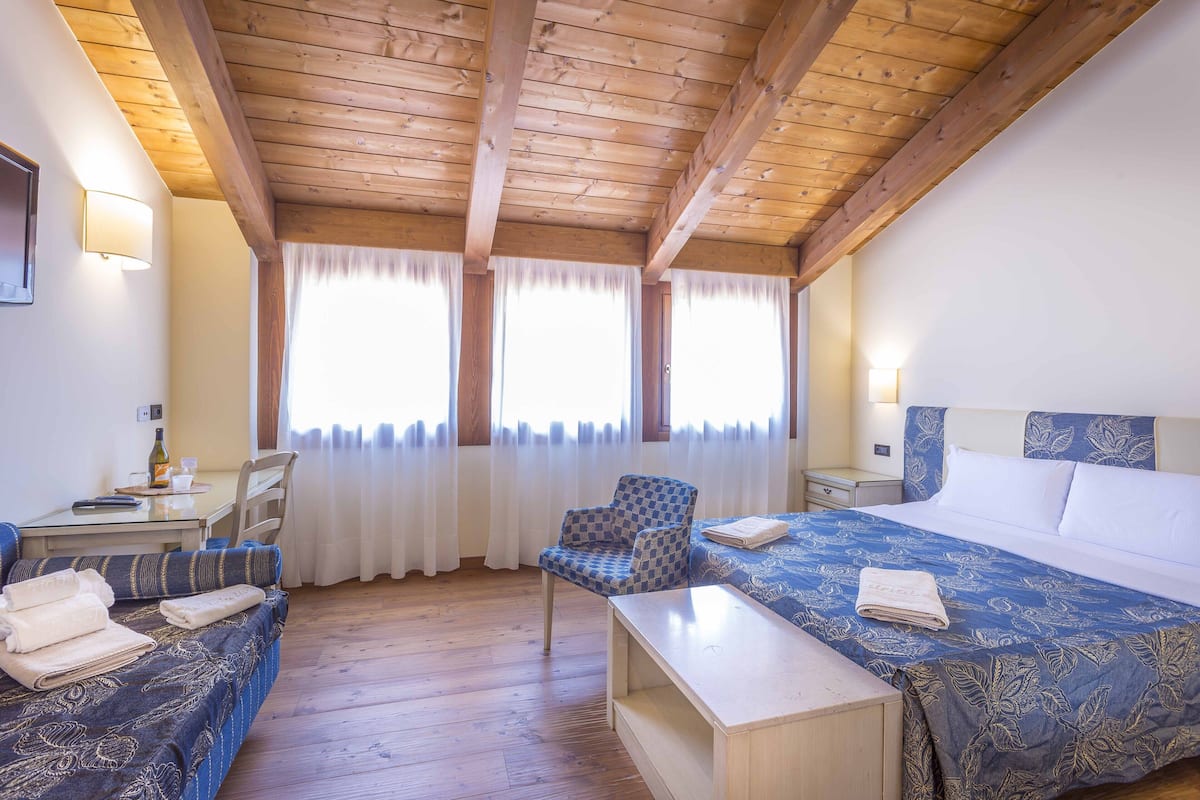 A room with a bed, a chair, a table, and a window with curtains.