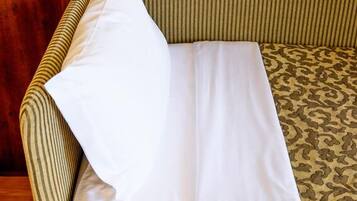 A hotel room with a bed, a sofa, and a wooden cabinet.