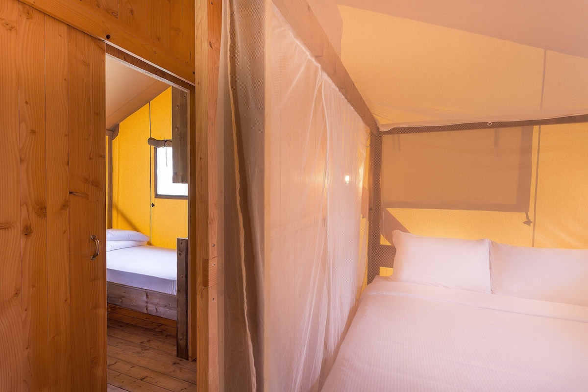 A bedroom with a wooden door, a bed with white bedding, and a window with a view.