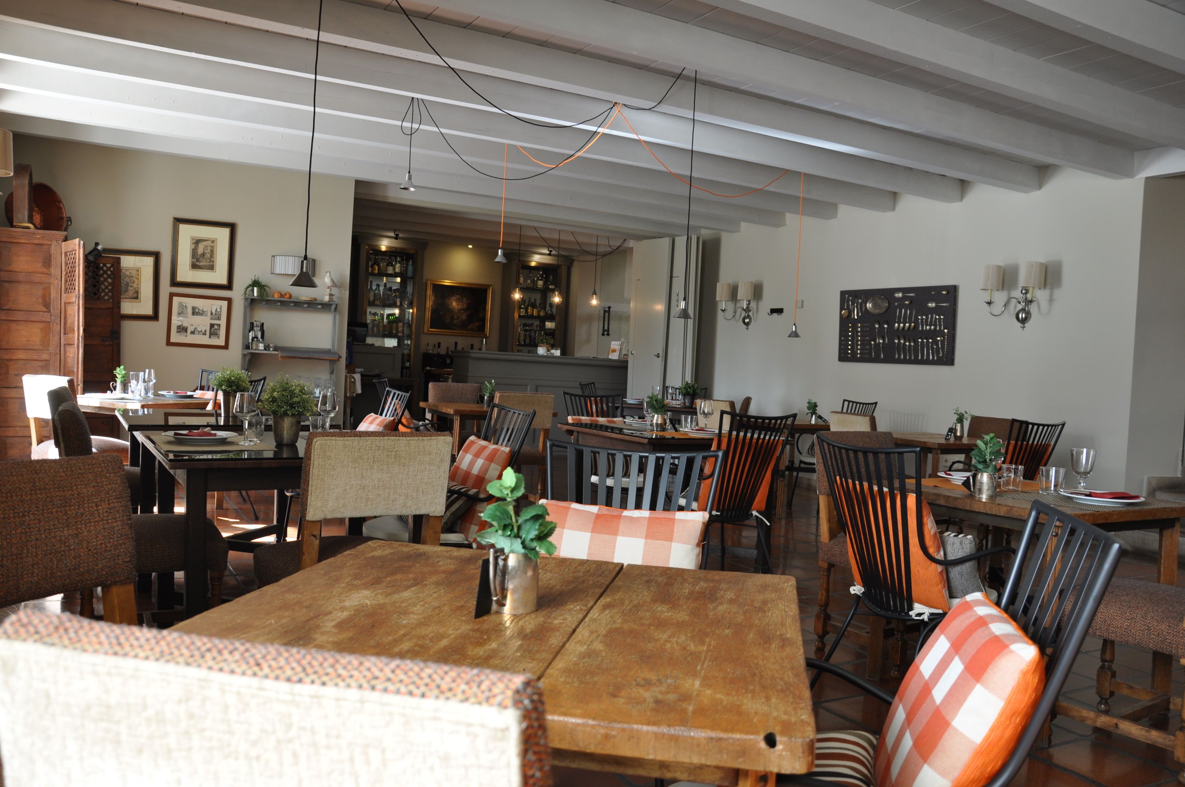 Un comedor amplio con mesas y sillas de madera, un bar al fondo y diversas decoraciones en las paredes.