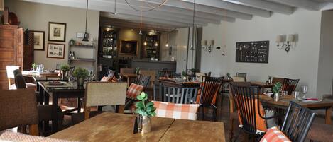 Un comedor amplio con mesas y sillas de madera, un bar al fondo y diversas decoraciones en las paredes.