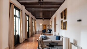A spacious hallway with a sofa, chairs, and a radiator.