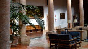 A spacious courtyard with a central seating area, columns, and a balcony with black railings.