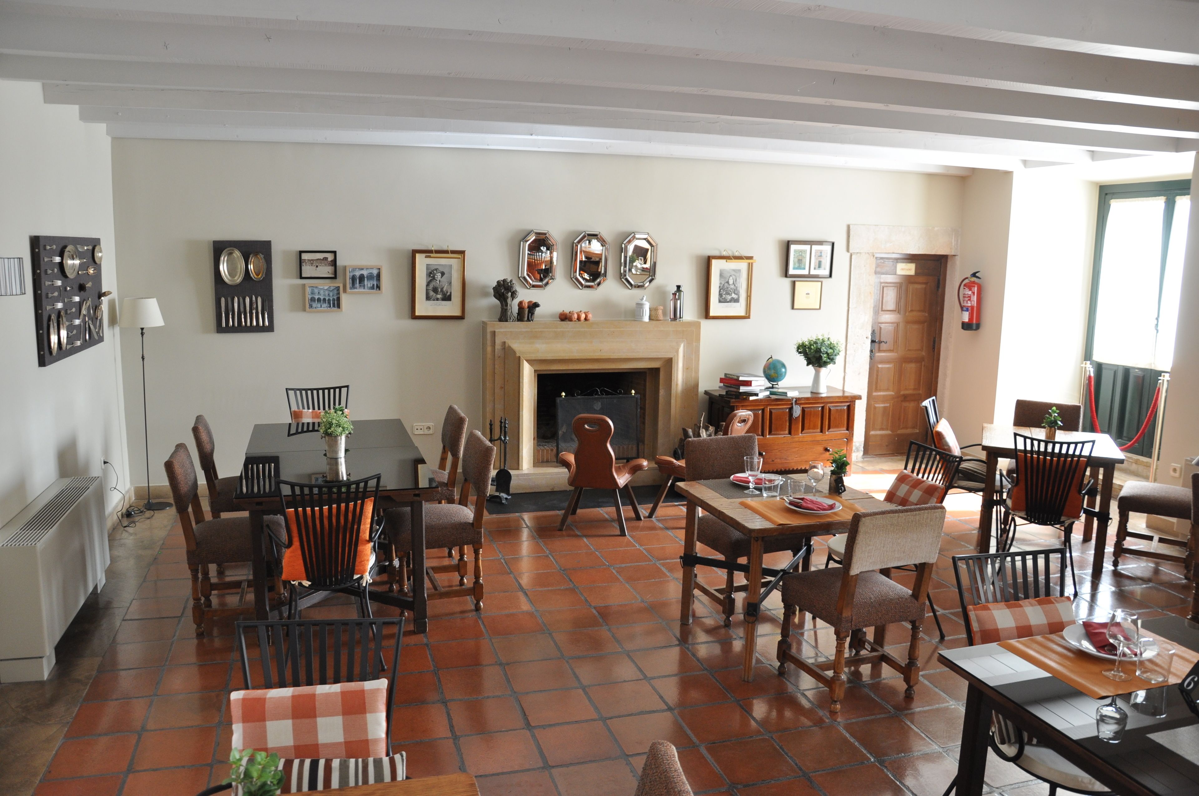 Un salón amplio con chimenea, suelo de baldosas y varias obras de arte en las paredes.