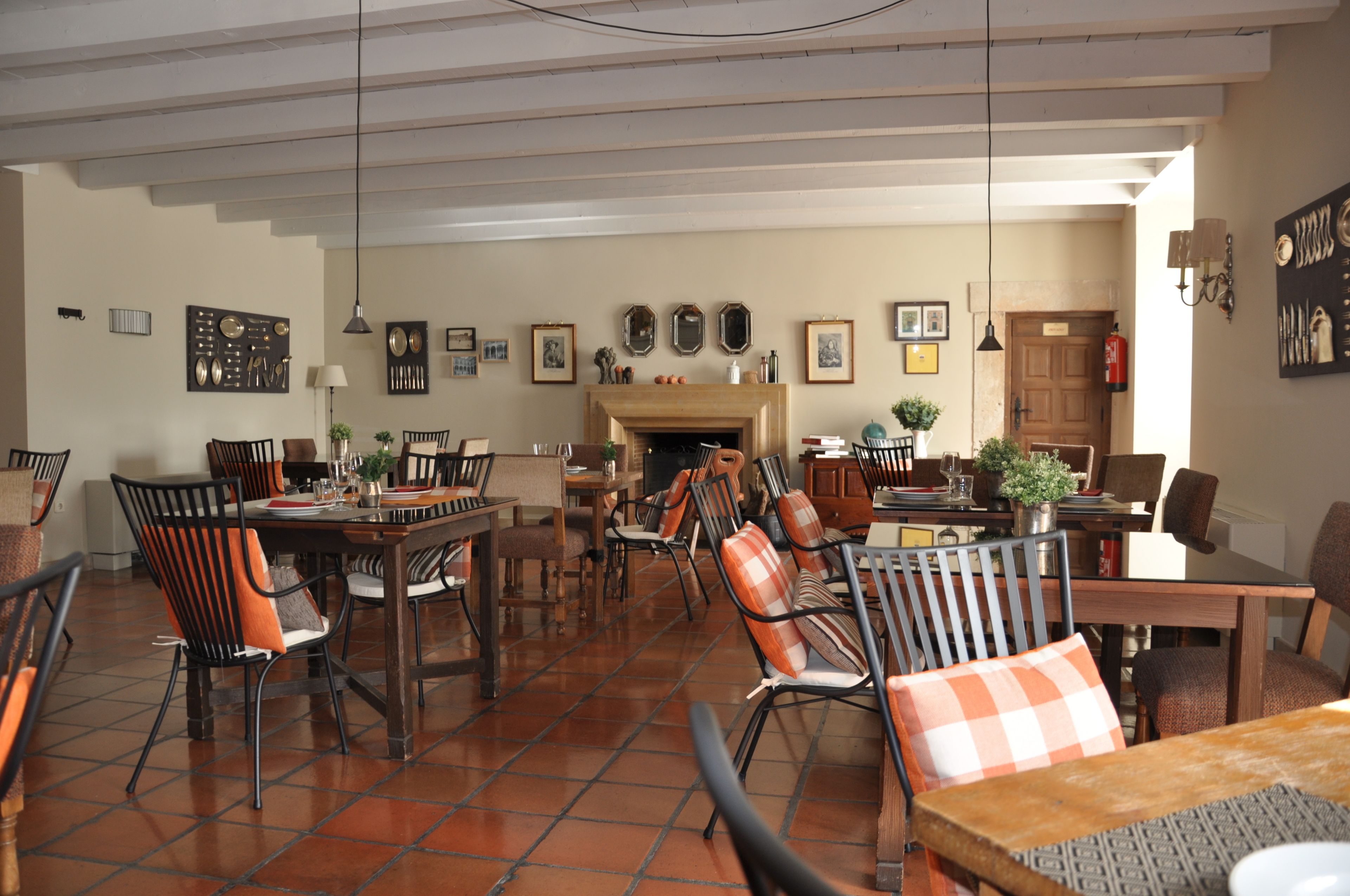 Un comedor amplio con varias mesas y sillas, una chimenea y diversas decoraciones en las paredes.