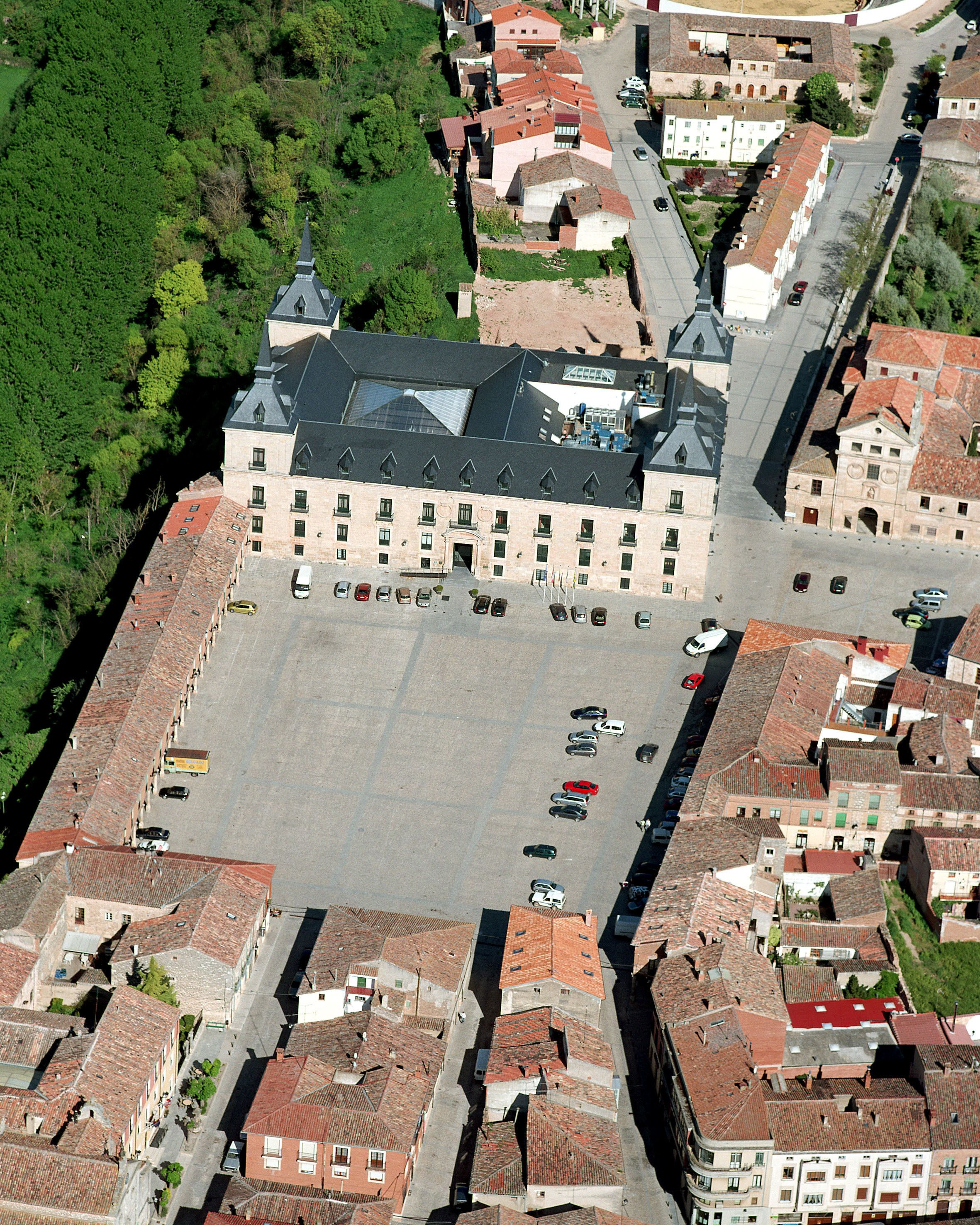 An aerial view of a historic building with a large courtyard, surrounded by narrow streets and traditional architecture.