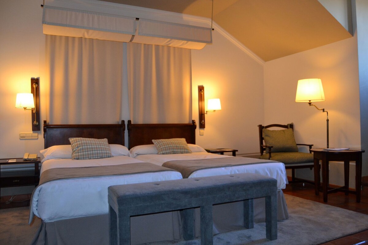 A hotel room with a large bed, two bedside tables, a chair, and a lamp.