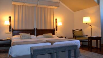 A hotel room with two beds, a chair, a desk, and a lamp.