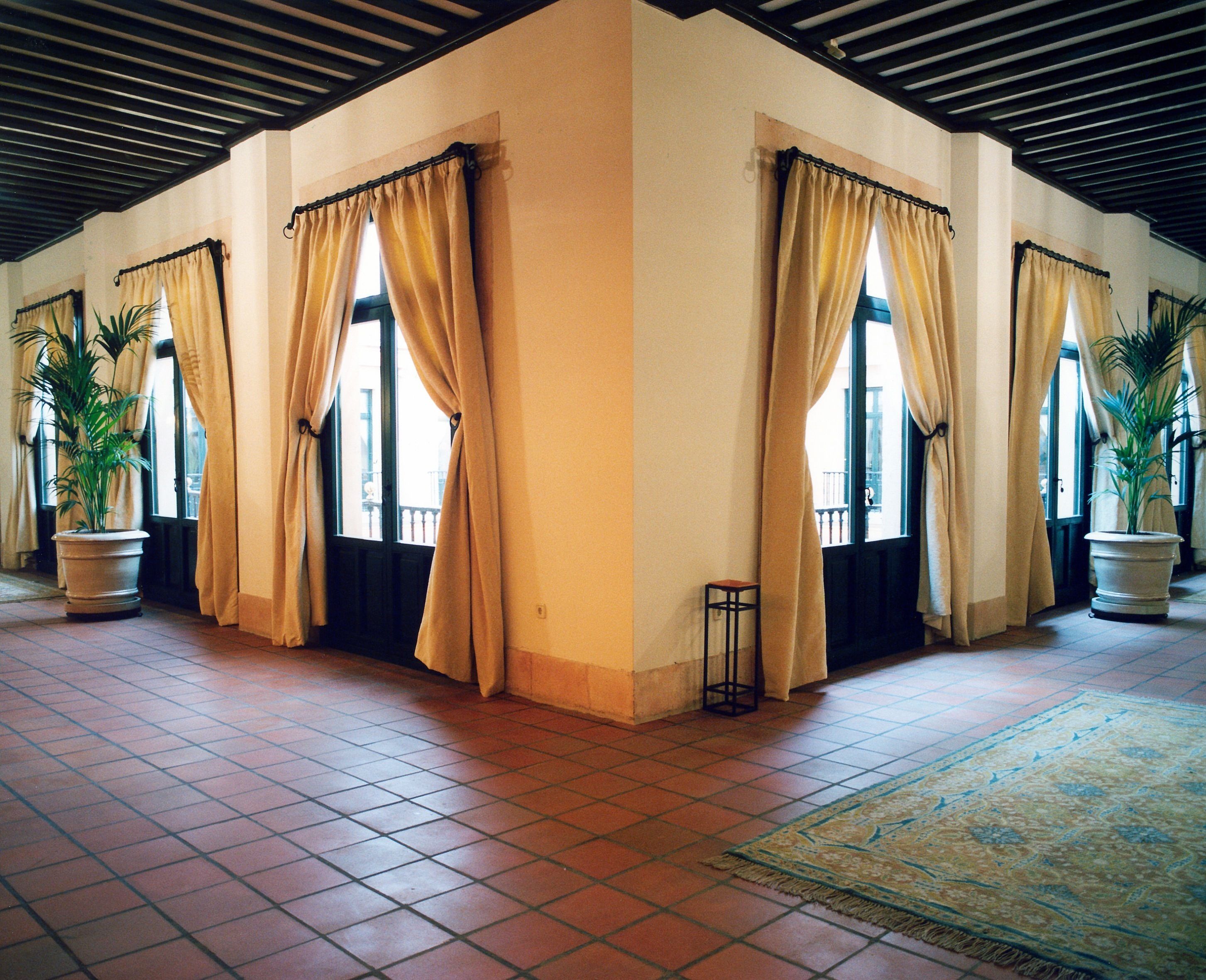 A spacious lobby with large windows, potted plants, and a tiled floor.