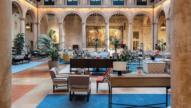 A spacious lobby with multiple seating areas, a central bar, and a large mural on the back wall.