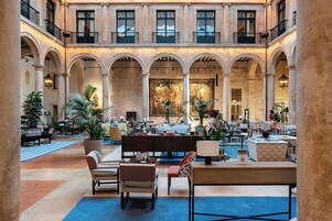 A spacious lobby with multiple seating areas, a central bar, and a large mural on the back wall.