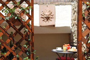 Estrutura de madeira treliçada com um relevo solar fixado na parede, uma mesa com itens de café da manhã e uma cadeira vermelha acolchoada.