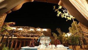 An outdoor dining setup with a table set for two, featuring a bottle of champagne, two wine glasses, and a plate of food. - Riad Mille et une Nuits (Marrakech)