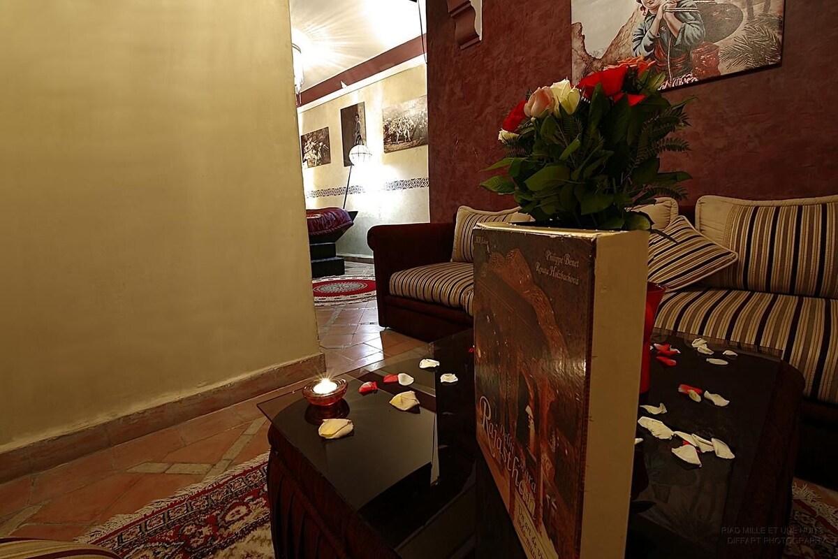 A cozy living area with a sofa, a small table with a candle, and a decorative vase with flowers.
