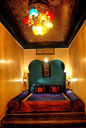 A room with a bed, a chandelier, and a wall-mounted picture. - Riad Mille et une Nuits (Marrakech)