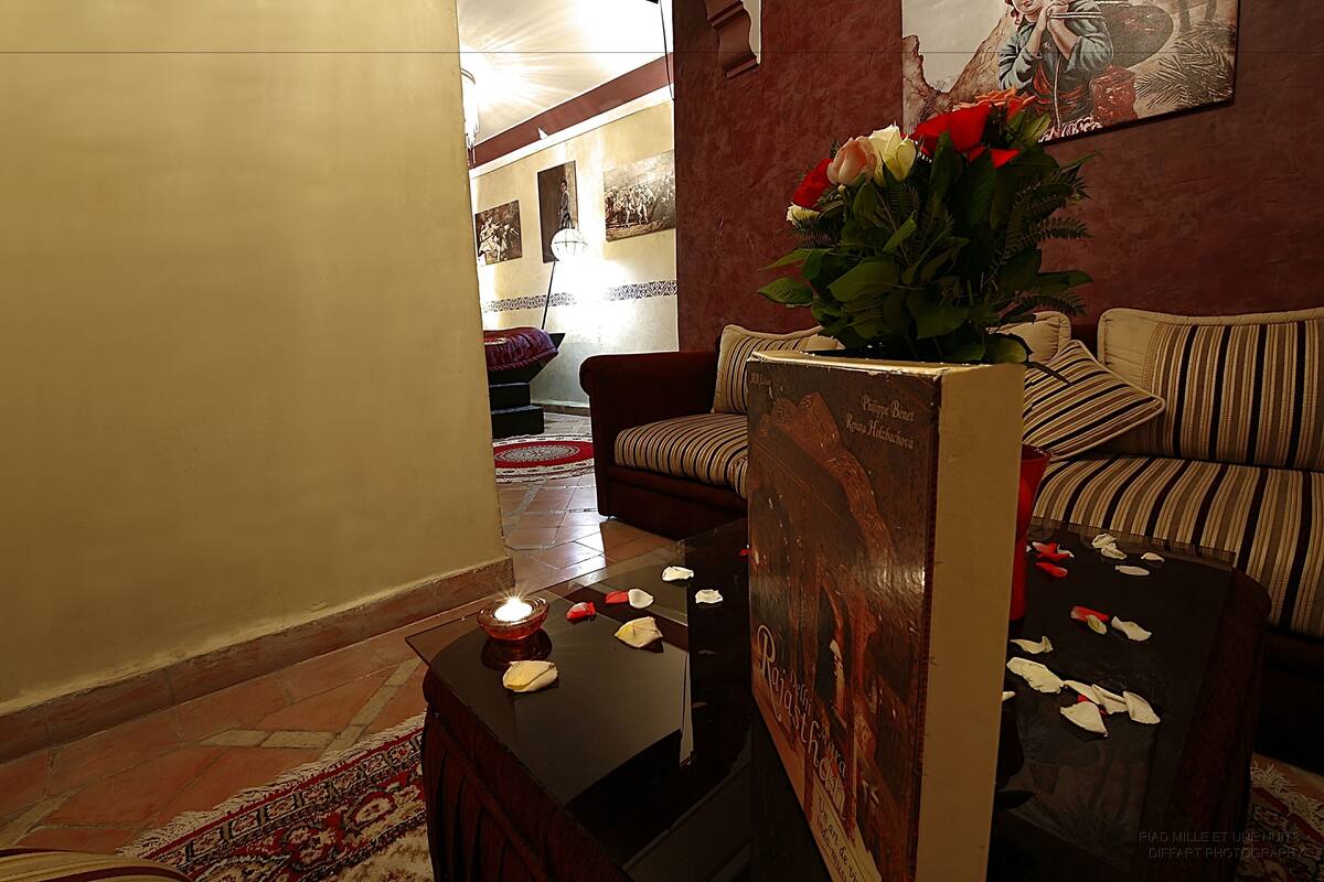 A lobby with a sofa, a small table with a candle, and a poster.