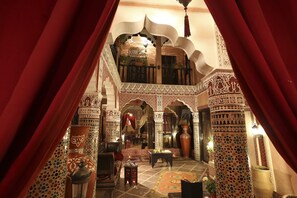 An ornate interior with a balcony, patterned walls, and traditional furnishings. - Riad Mille et une Nuits (Marrakech)
