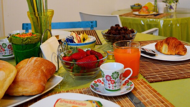 Una mesa de desayuno con diferentes alimentos, un cuadro de una playa y una silla.