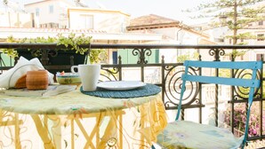 Un balcón con una mesa para dos, una silla y vistas a edificios al fondo.