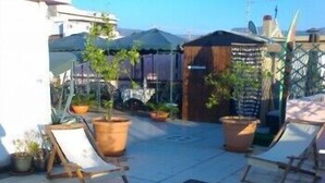 Terraza en la azotea con dos sillones de relax, plantas en macetas y una piscina pequeña.