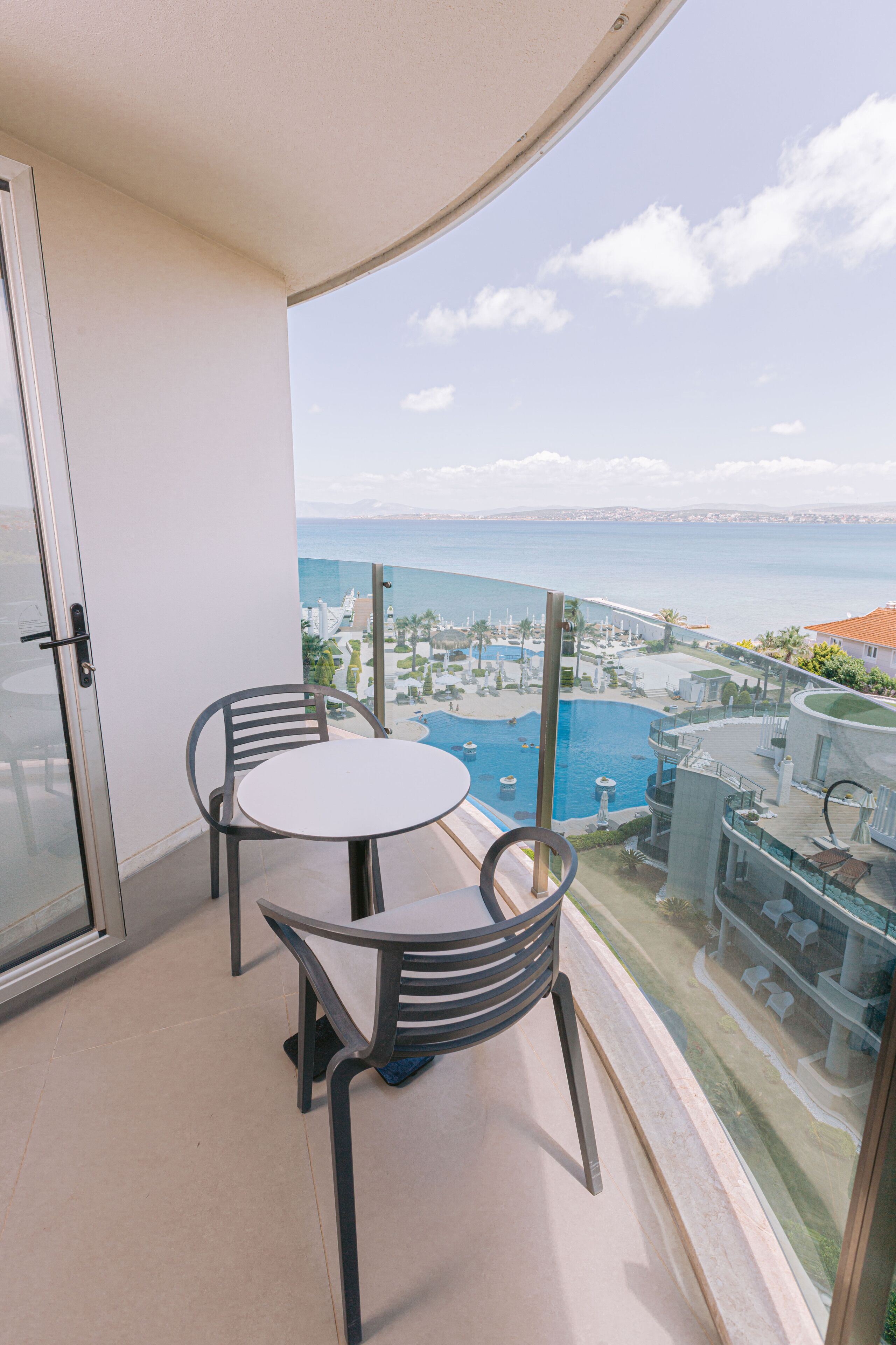 A balcony with a glass door, two chairs, and a small table.
