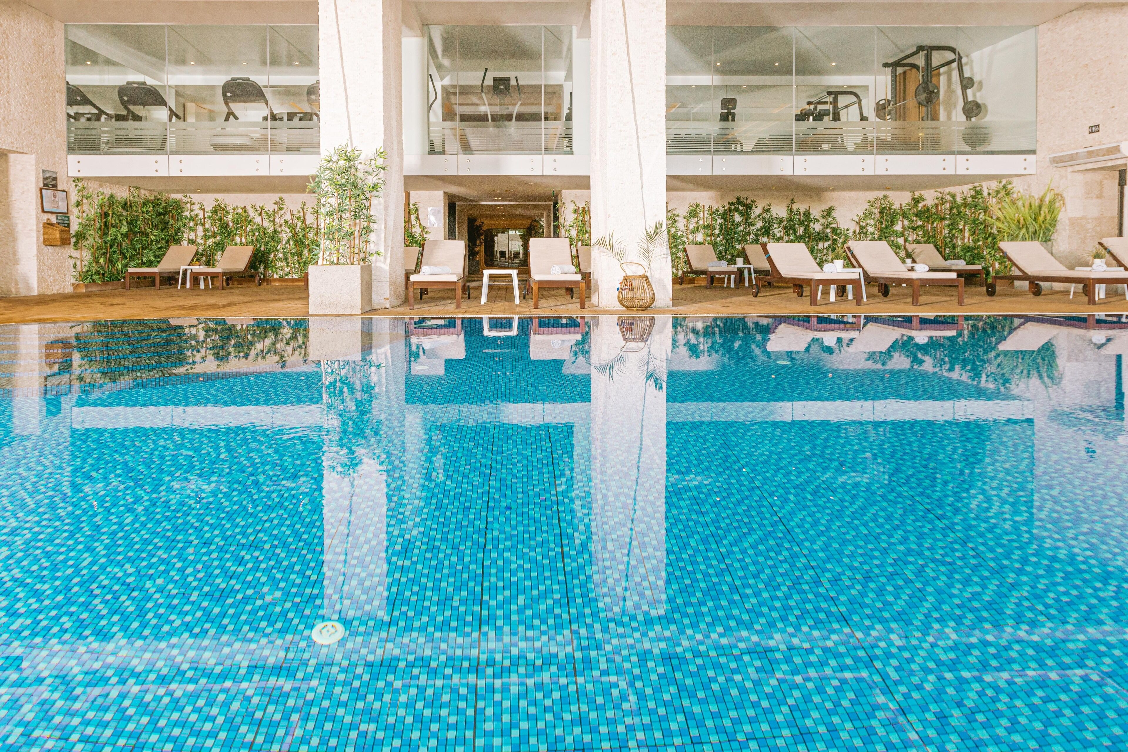 Piscina com espreguiçadeiras e plantas em vasos ao redor.