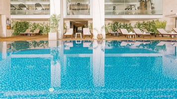 Piscina com espreguiçadeiras e plantas em vasos ao redor.