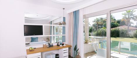 A modern bedroom with a large window, a desk, a bed, and a TV.