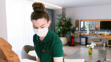 A person cleaning a wooden table in a modern living room with a sofa, a coffee table, and a plant in the background.