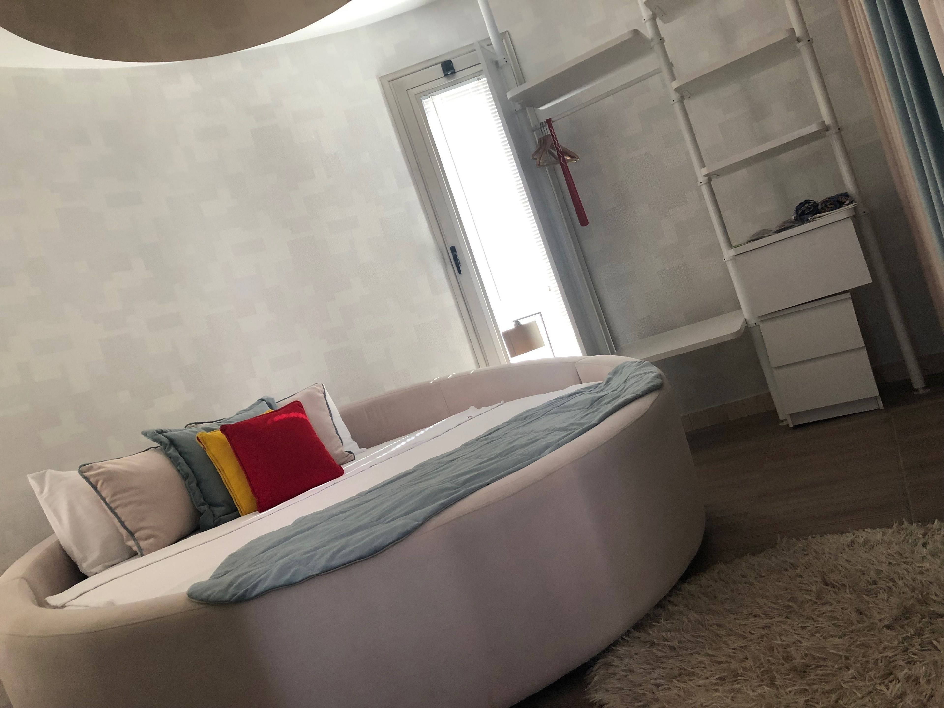 Un dormitorio moderno con una cama curvada, un armario blanco y una alfombra mullida.