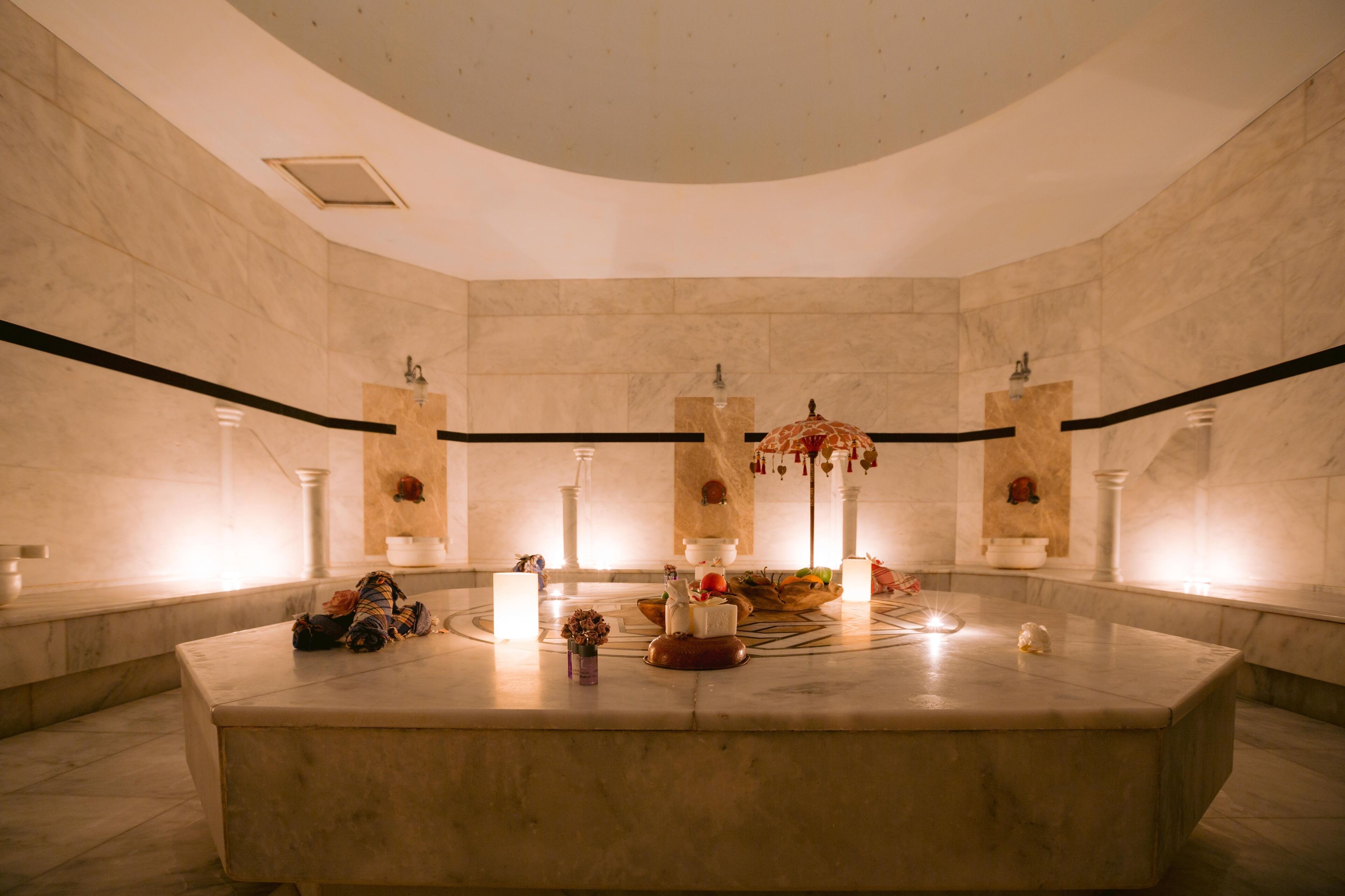 A luxurious bathroom with a marble vanity, a large mirror, and a decorative fountain centerpiece.