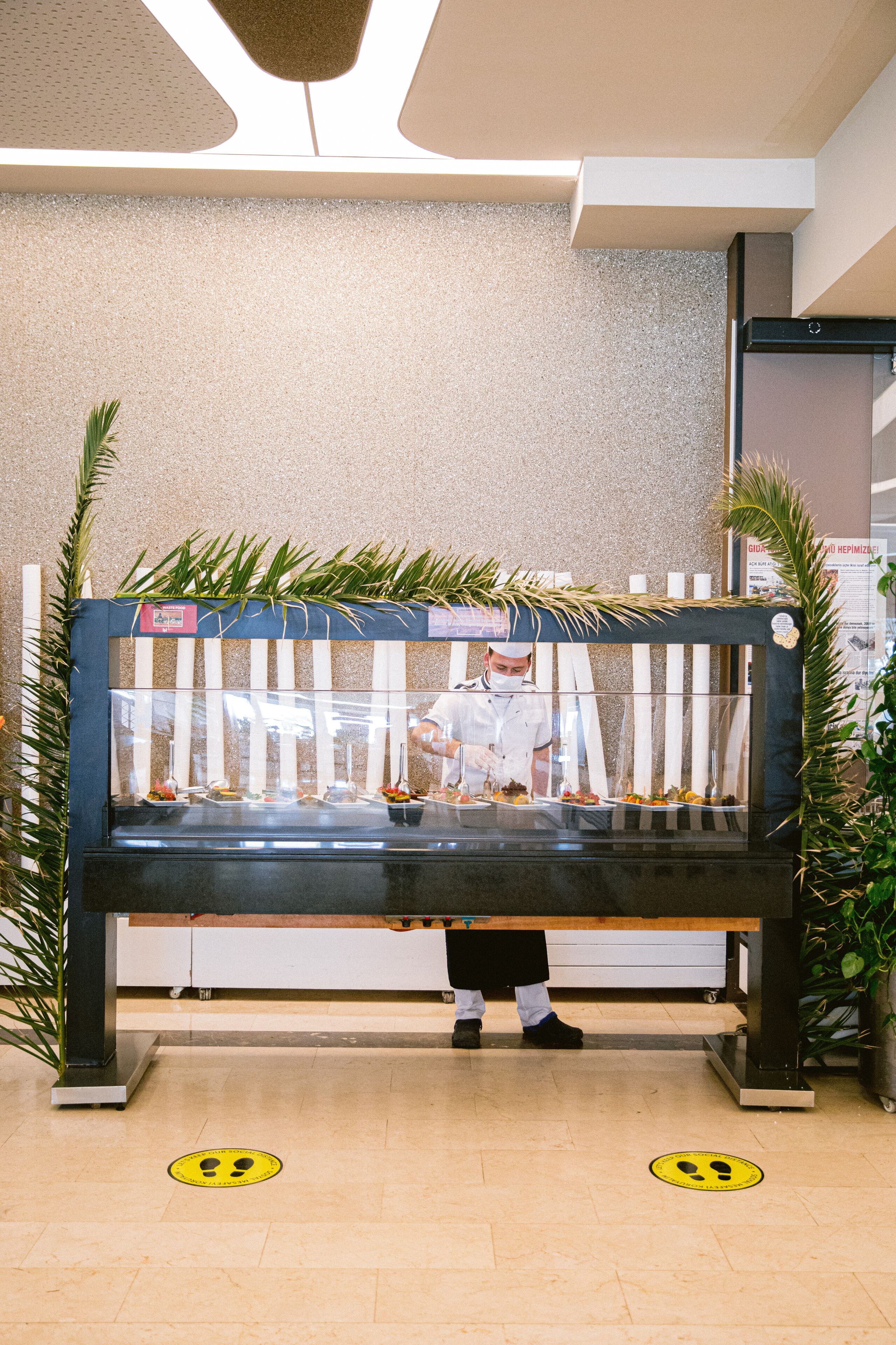 A bench with a glass enclosure, a chef preparing food, and a wall with a textured pattern.