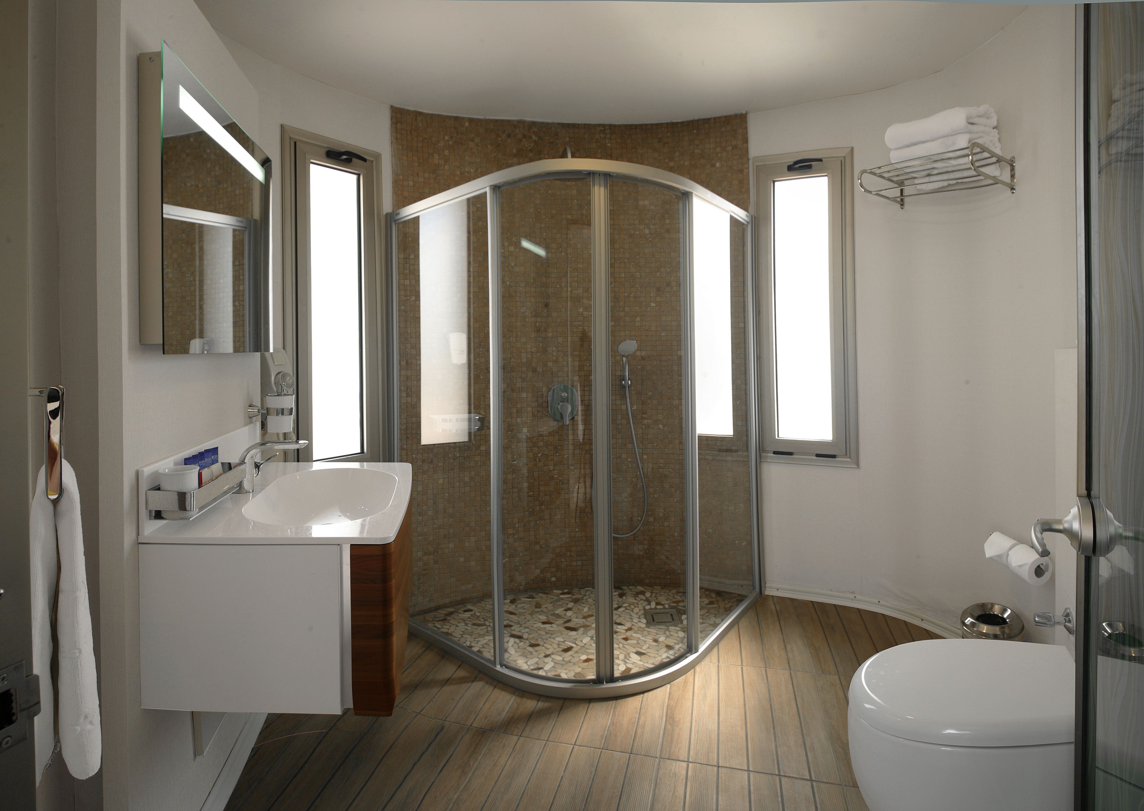 A modern bathroom with a glass-enclosed shower, a white sink, and a toilet.