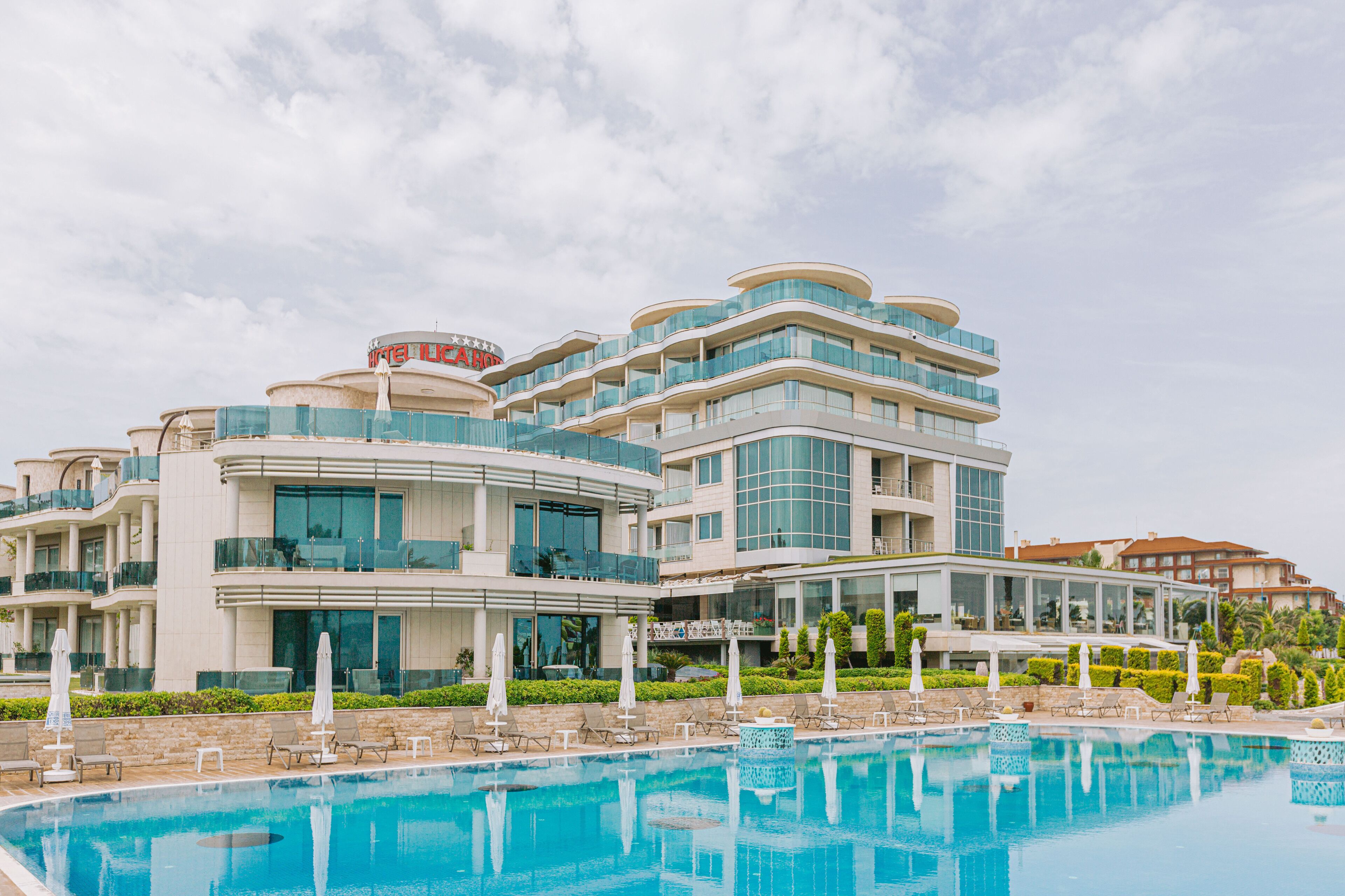 Un hôtel moderne doté d’une grande piscine, de nombreux balcons et d’espaces extérieurs aménagés pour se détendre.