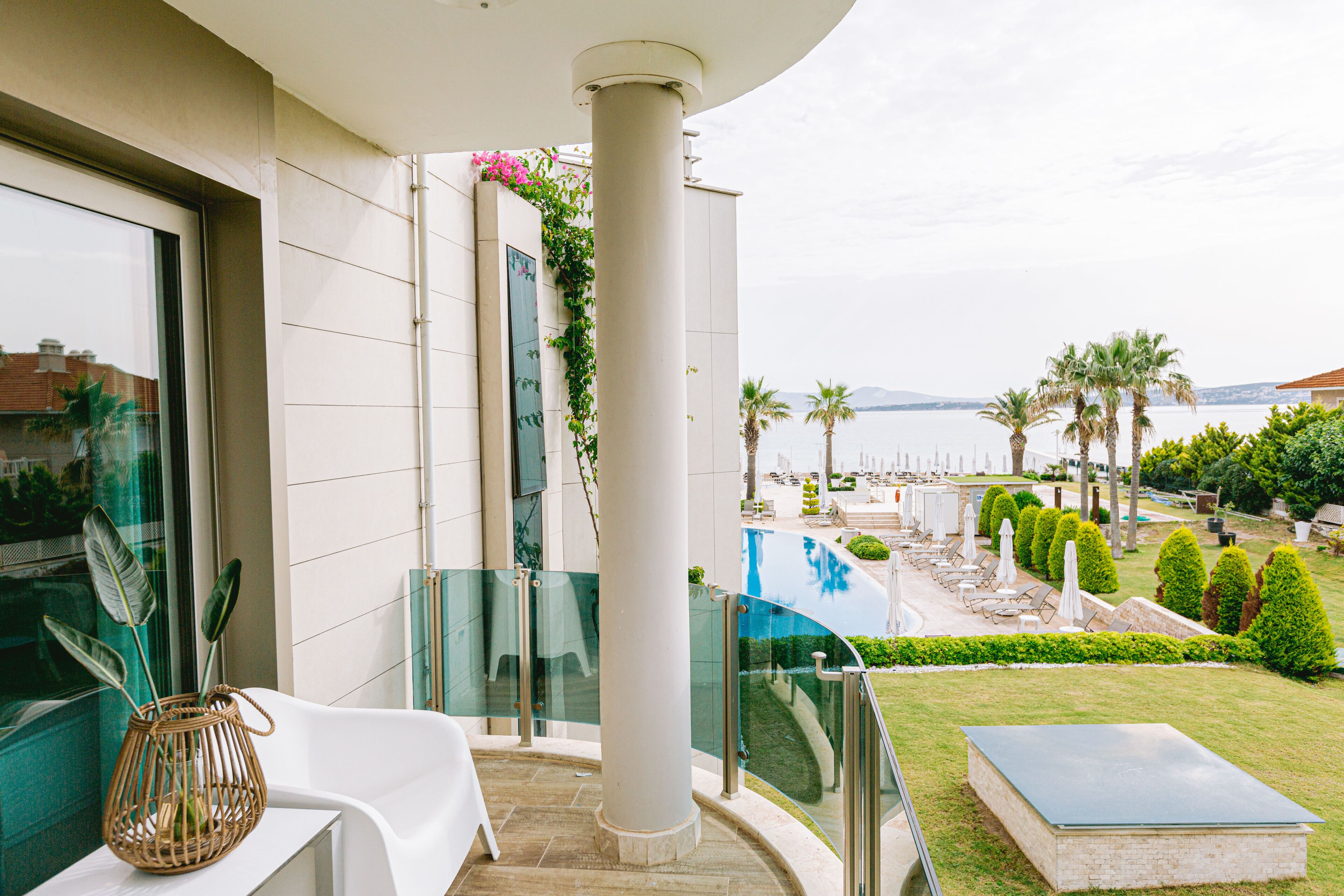 A balcony with a glass railing overlooking a pool and garden.