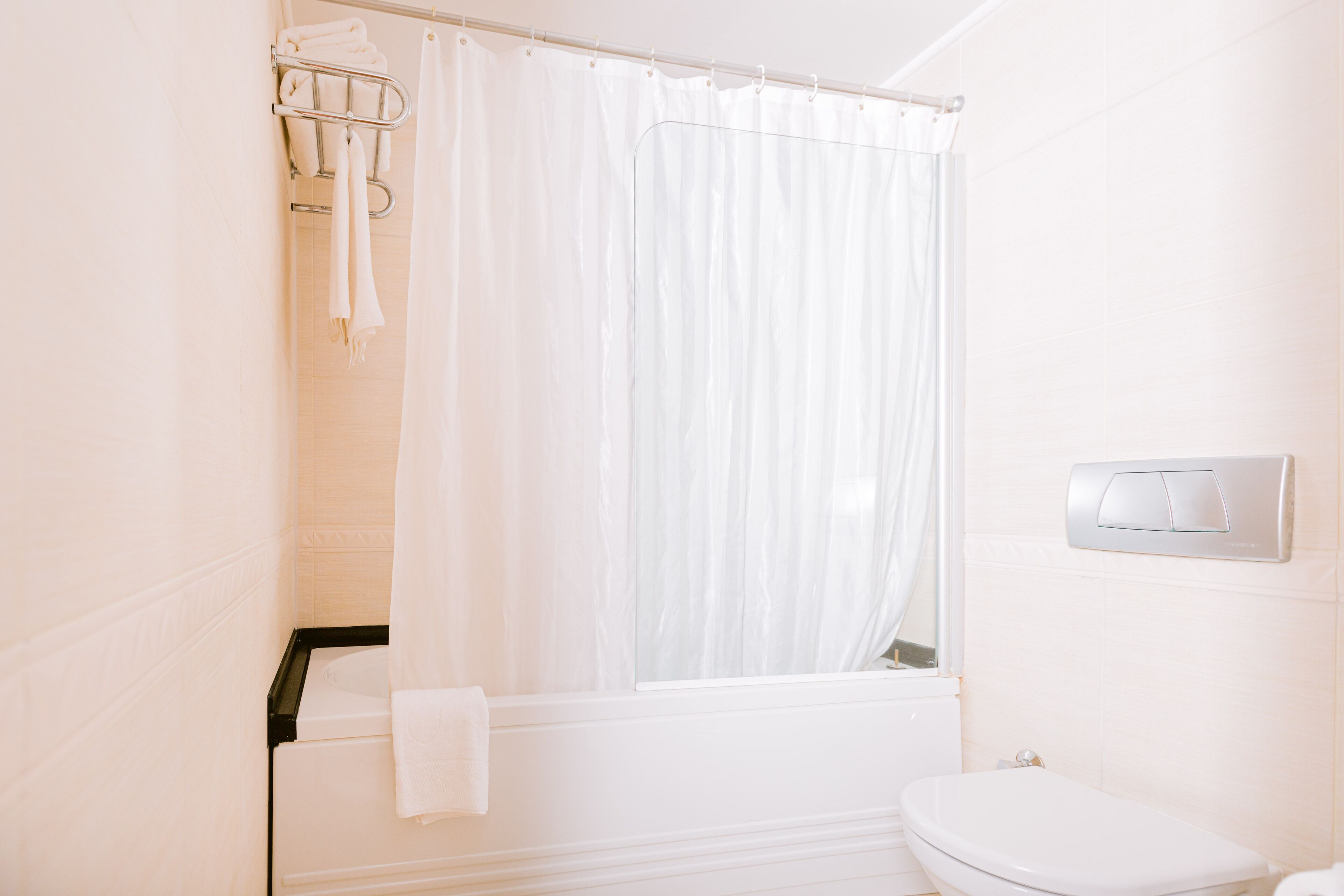 Baño con ducha, inodoro y perchero.