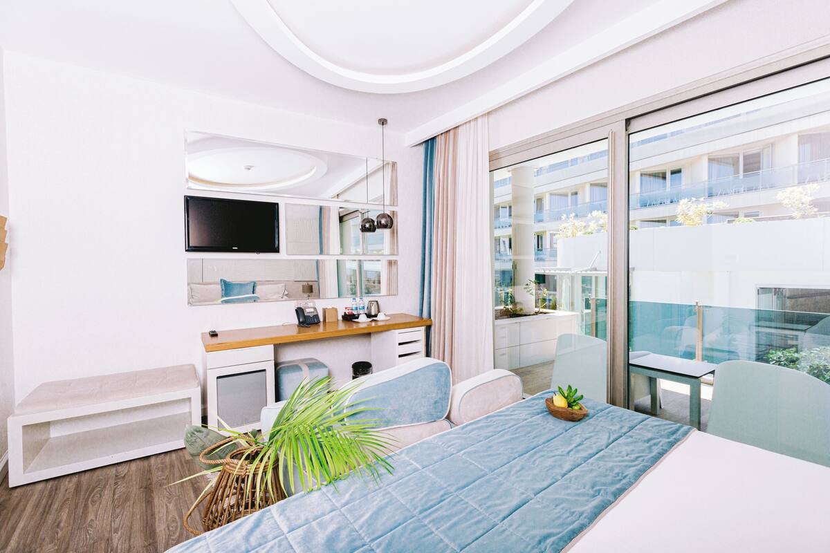 A modern hotel room with a bed, desk, and large window.