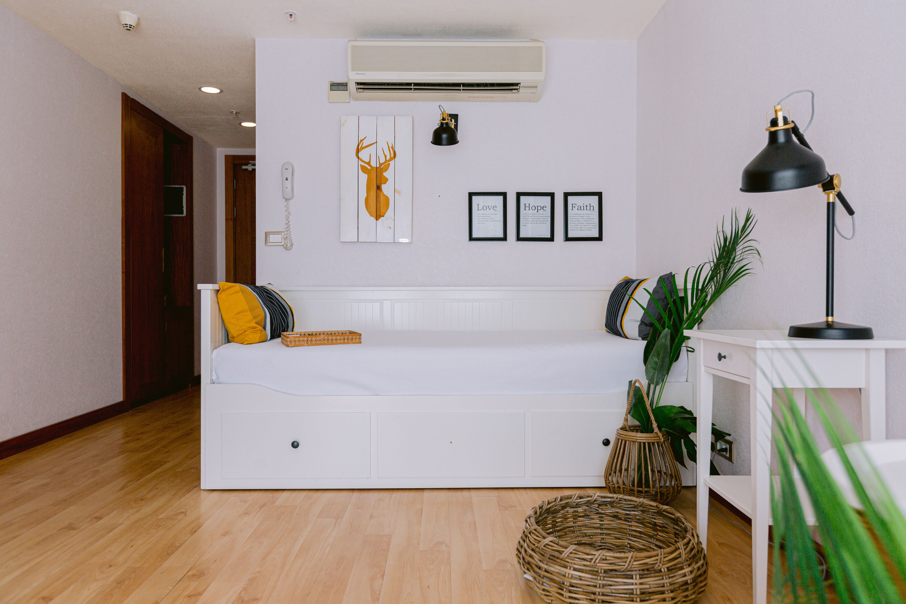Ein modernes Wohnzimmer mit einem weißen Sofa, einer schwarzen Stehlampe und einer Wand-Klimaanlage.